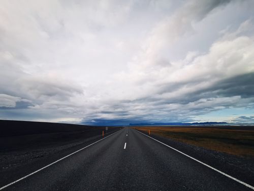 Free An empty road stretching through the vast Icelandic plains under a cloudy sky. Stock Photo