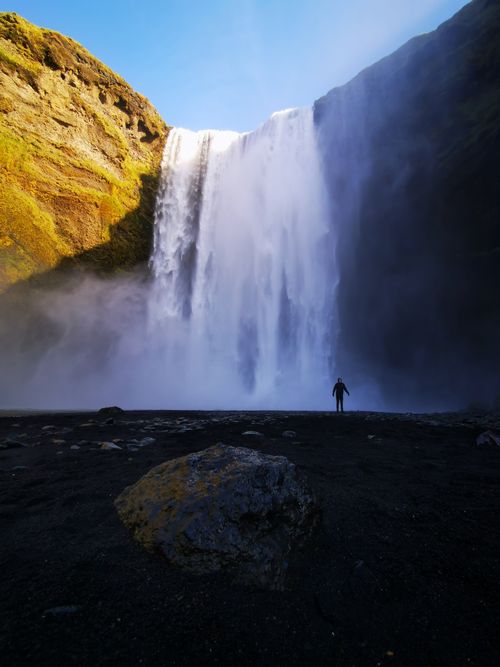 Free A breathtaking view of Skógafoss waterfall with a silhouette, capturing Iceland's natural beauty. Stock Photo