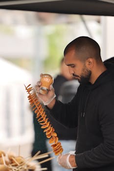 A vendor skillfully seasons spiral potato snacks at an outdoor market in Jönköping, Sweden.
