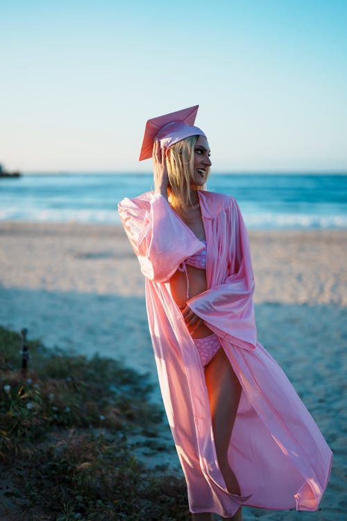 graduate wearing a cap gown bikini at beach