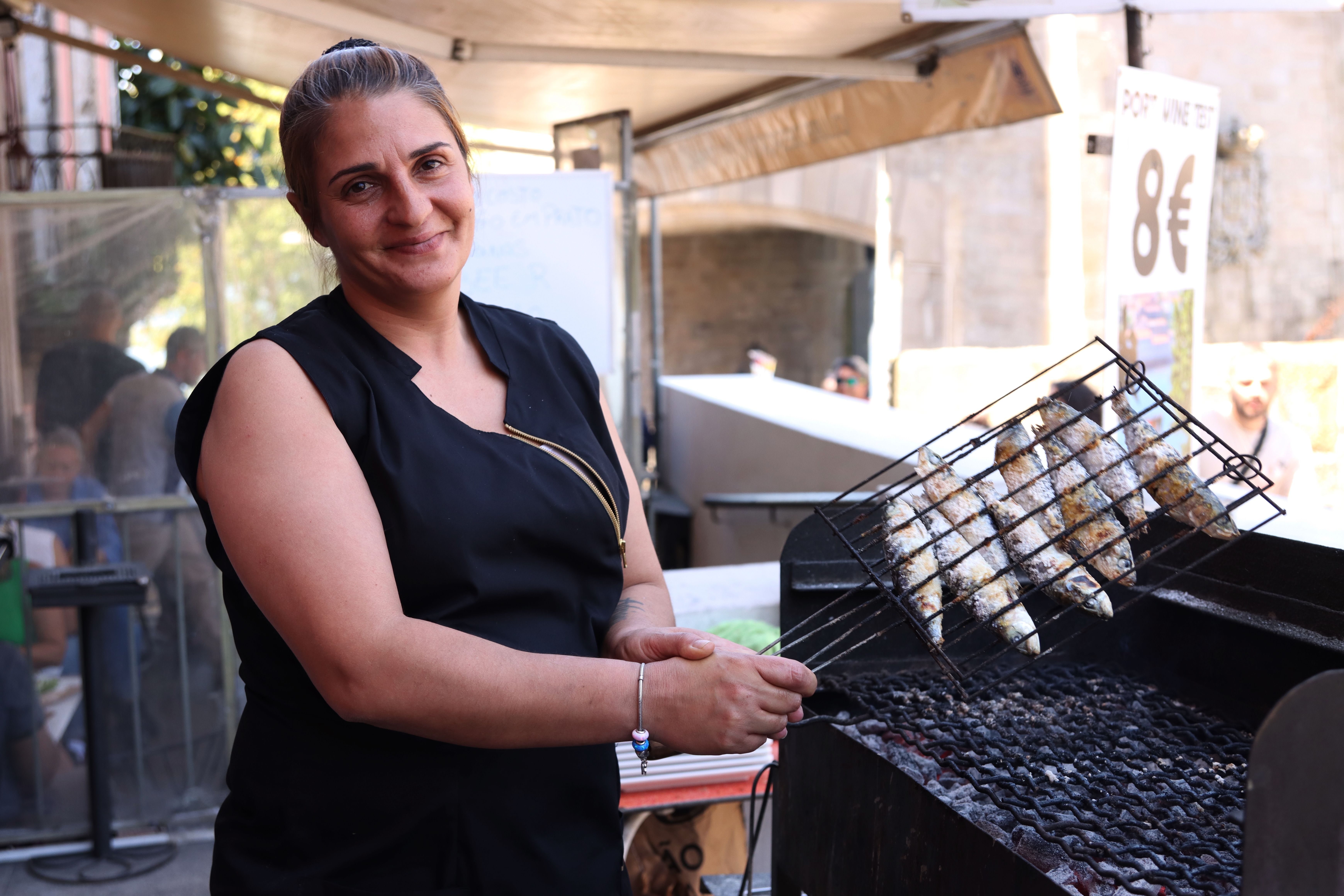 A chef grilling fresh fish at an outdoor food stall in Porto