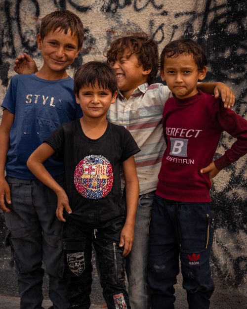 Free Group of four boys smiling and embracing against graffiti wall background Stock Photo