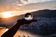 手持水晶球捕捉城市景观中令人惊叹的日落，创造出神奇的倒影