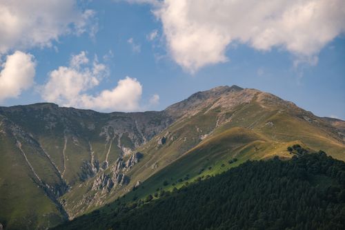 Free Beautiful green mountains under a bright blue sky with clouds. Perfect for nature themes. Stock Photo
