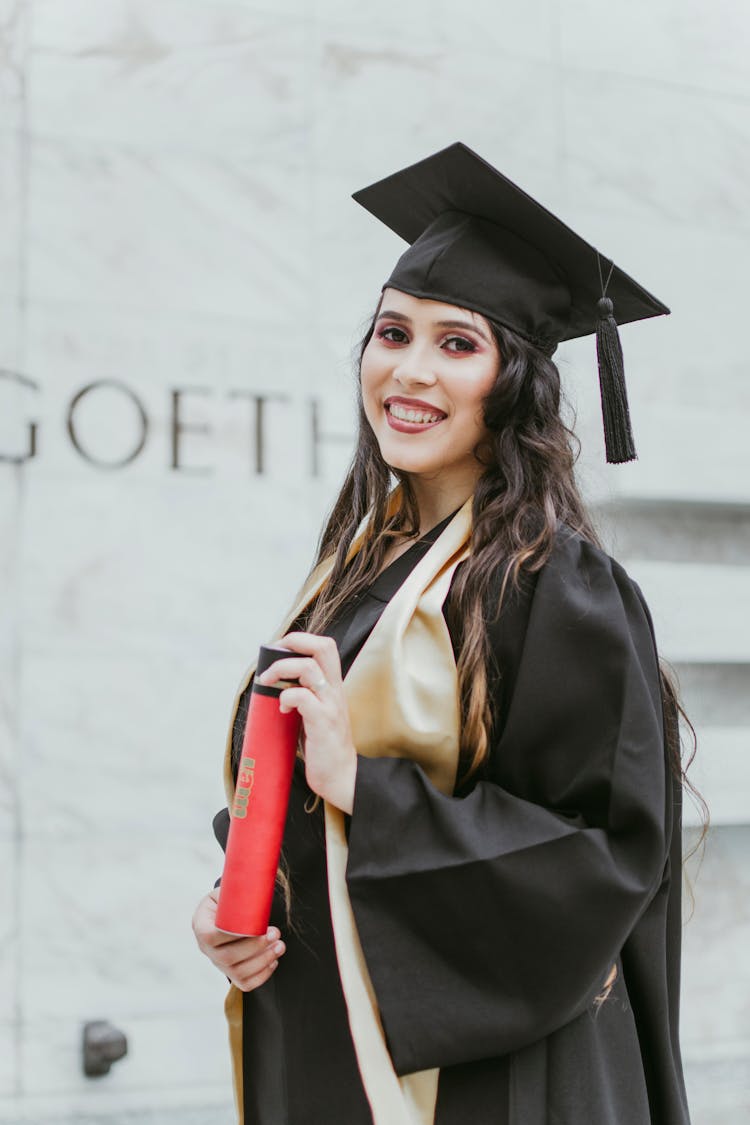 Selective Focus Photo Of Smiling Woman In Black Academic Dress Holding Diploma Posing