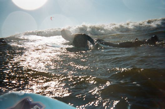 A surfer paddles through shimmering ocean waves under a glowing sunset, capturing a moment of pure adventure.