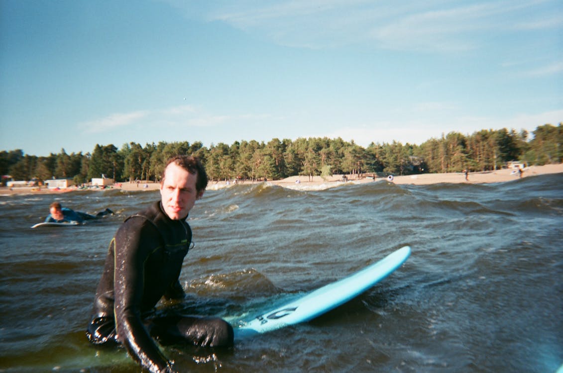 Man Resting on His Surfboard at the Beach