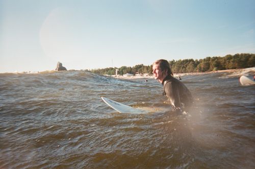 Free A surfer smiles widely while riding the waves on a bright, sunny day at the beach. Stock Photo