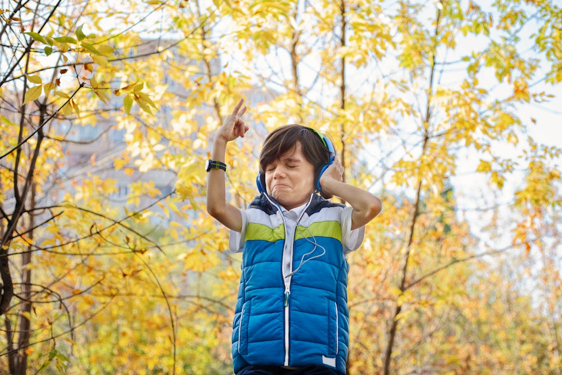 Man Wearing Blue Vest Standing Beside Tree