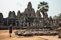 旅行者在柬埔寨吴哥窟探索古老的巴戎寺，周围环绕着令人惊叹的建筑