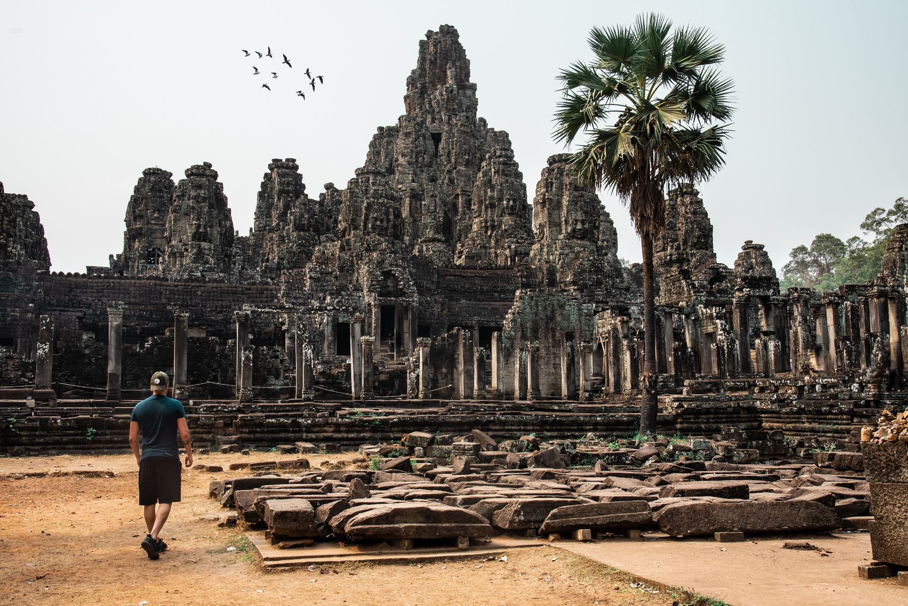 Traveler walking among the carved stone face towers of Bayon at Angkor Thom