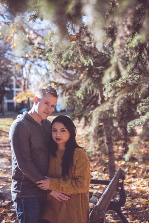 Free A couple embracing on a park bench surrounded by autumn leaves, creating a warm, romantic atmosphere. Stock Photo