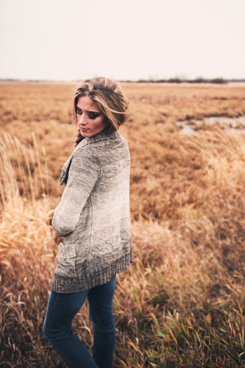 Photo of Woman Wearing Cardigan Standing on Grass Field