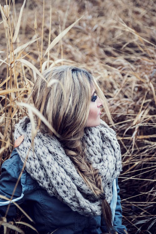 Selective Focus Photo of Woman Sitting on Grass Field Looking Away