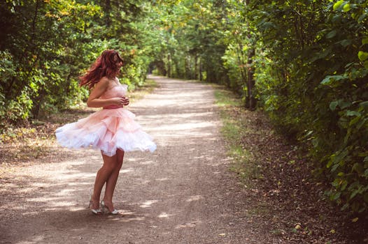 明媚的夏日，一名身穿粉色连衣裙的年轻女子在森林小路上快乐地旋转