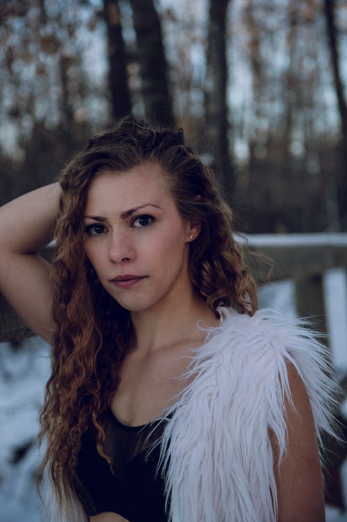 Selective Focus Portrait Photo of Woman in Black Crop Top and White Sleeveless Fur Coat Posing