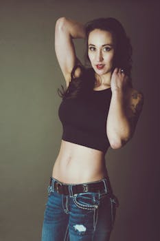 一位穿着休闲露脐上衣和牛仔裤的时尚女士，自信地摆出姿势