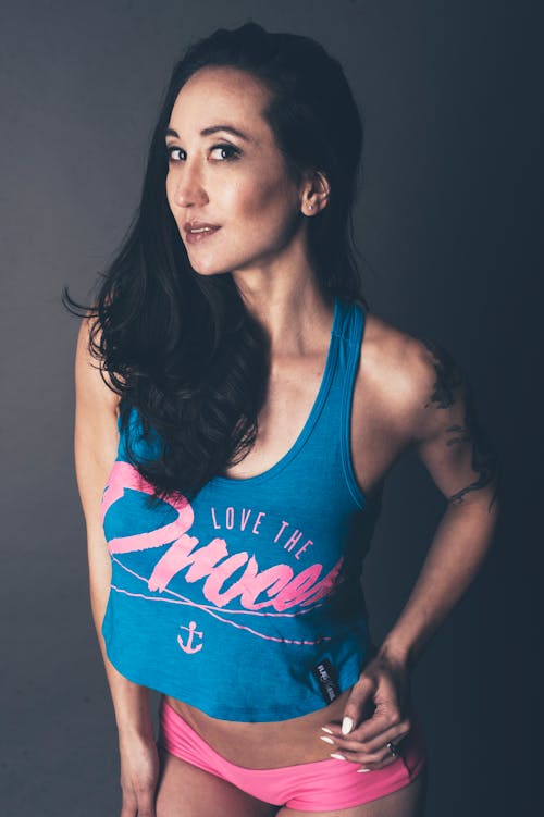 Photo of Woman in Blue Tank Top and Pink Panties Posing In Front of Gray Background