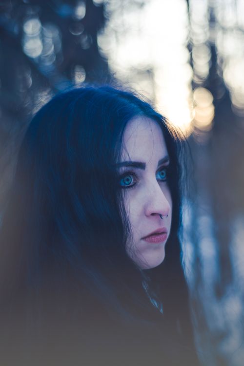Free A serene portrait of a woman with striking eyes in a winter forest setting. Stock Photo