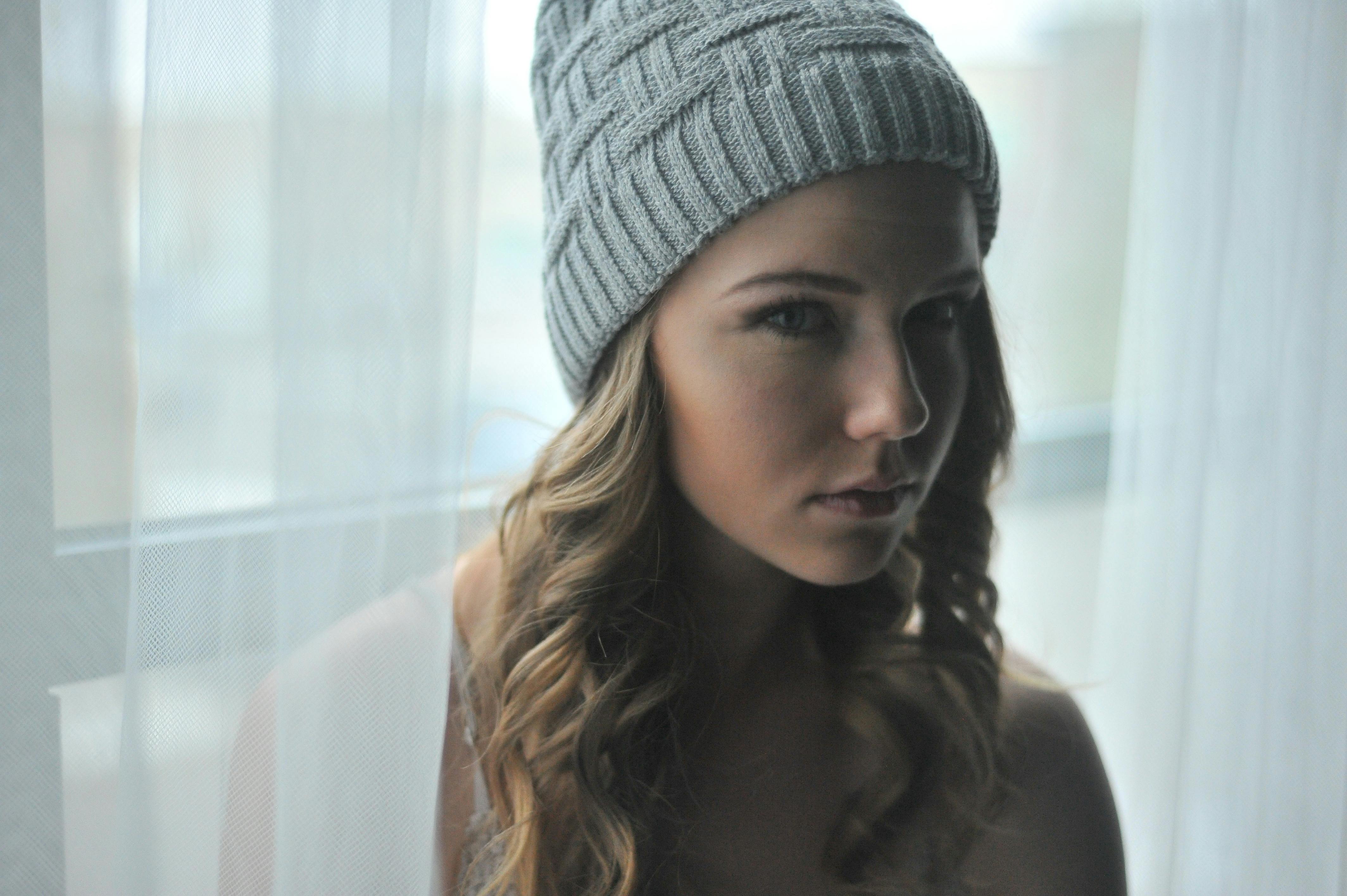 一位喜怒无常的女子，戴着针织无檐帽向外望去