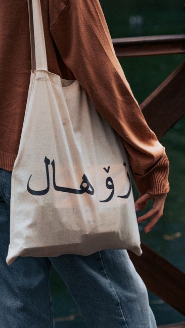 Stylish eco-friendly canvas tote bag with Arabic text in a cityscape setting for modern fashion enthusiasts. - Price and Value Considerations When Buying Handbags