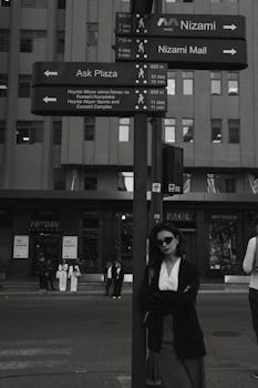 Elegant woman posing by city signs in Baku's urban landscape, exuding fashion and style.