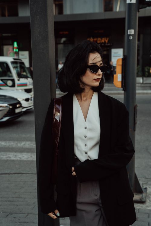 Free Stylish woman in sunglasses and black blazer poses on a vibrant city street in Baku, Azerbaijan. Stock Photo