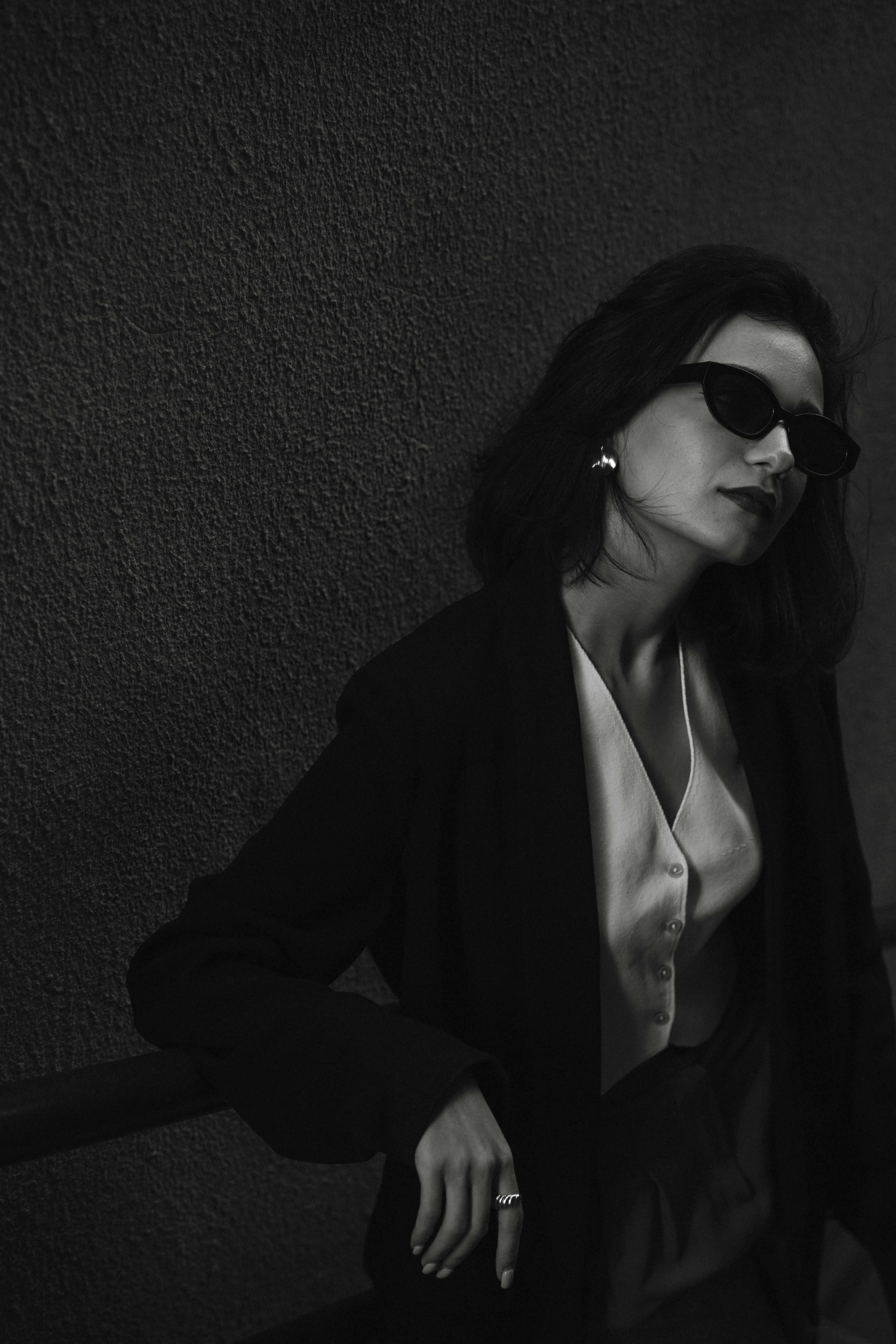 Black and white portrait of an elegant woman wearing sunglasses and a sophisticated outfit.