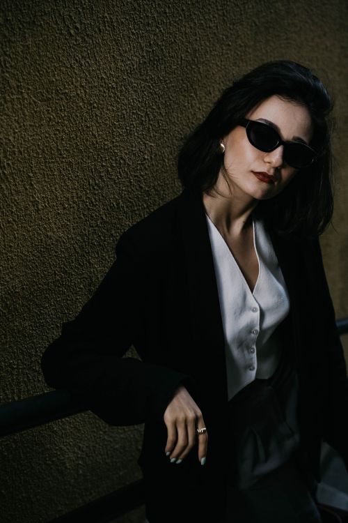 Free Elegant woman in sunglasses poses against a textured wall. Fashion photography captured in Baku, Azerbaijan. Stock Photo