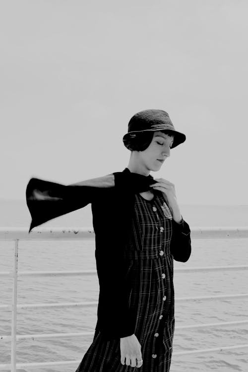 A woman in a hat and dress standing on a boat