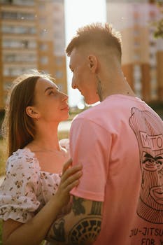 A young couple embraces under the warm sunrise, surrounded by urban architecture.
