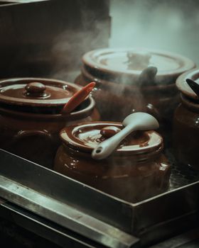 Steam rising from pots with colorful spoons adds a cozy kitchen vibe. Perfect for cooking themes.