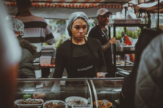 Street food vendor in a bustling São Paulo market preparing traditional dishes.