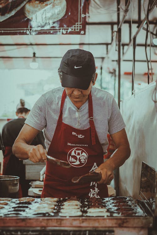 A man in a red apron is cooking food