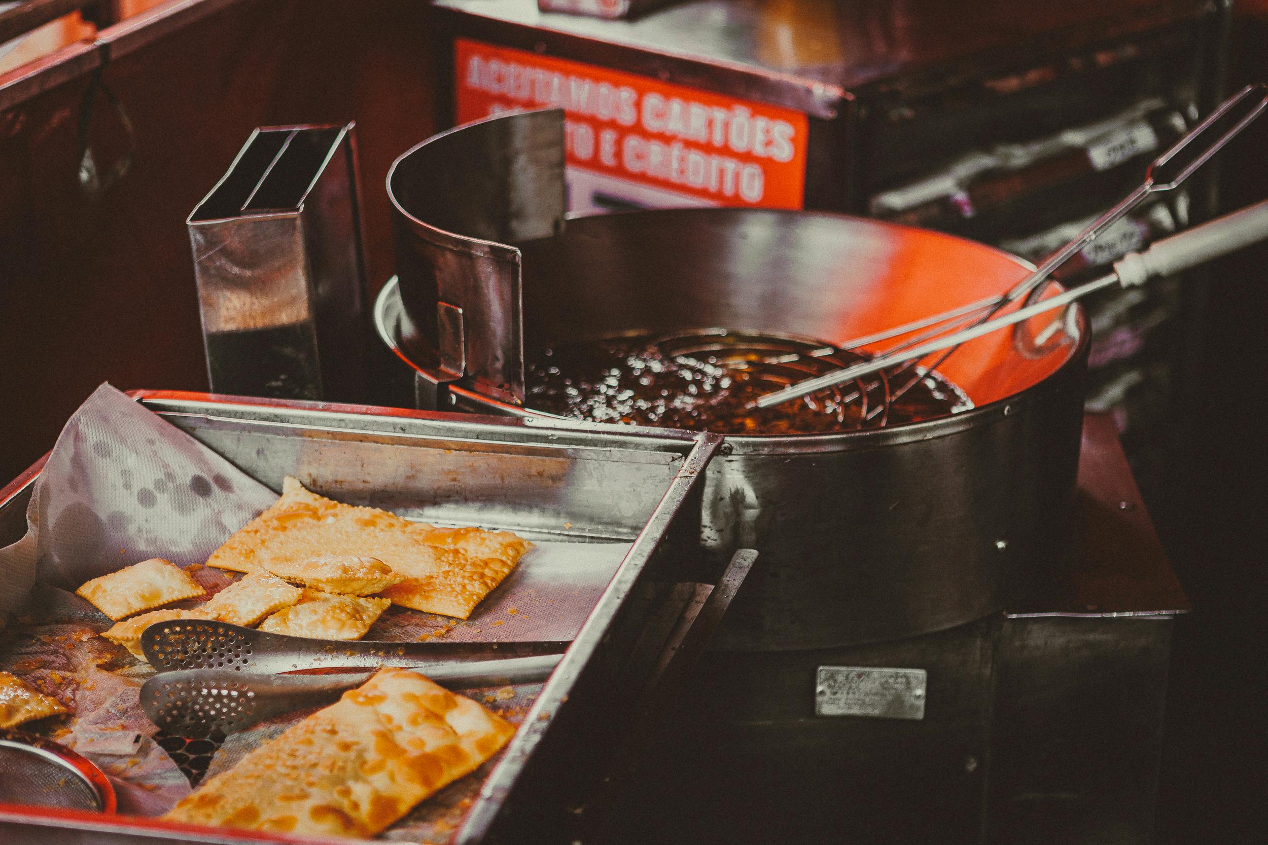 Delicious crispy pastries being fried at a vibrant street food stall in São Paulo, Brazil.
