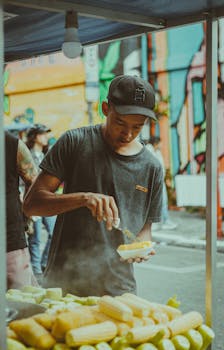 Young man cooking street food in vibrant São Paulo market. Urban setting with colorful background.