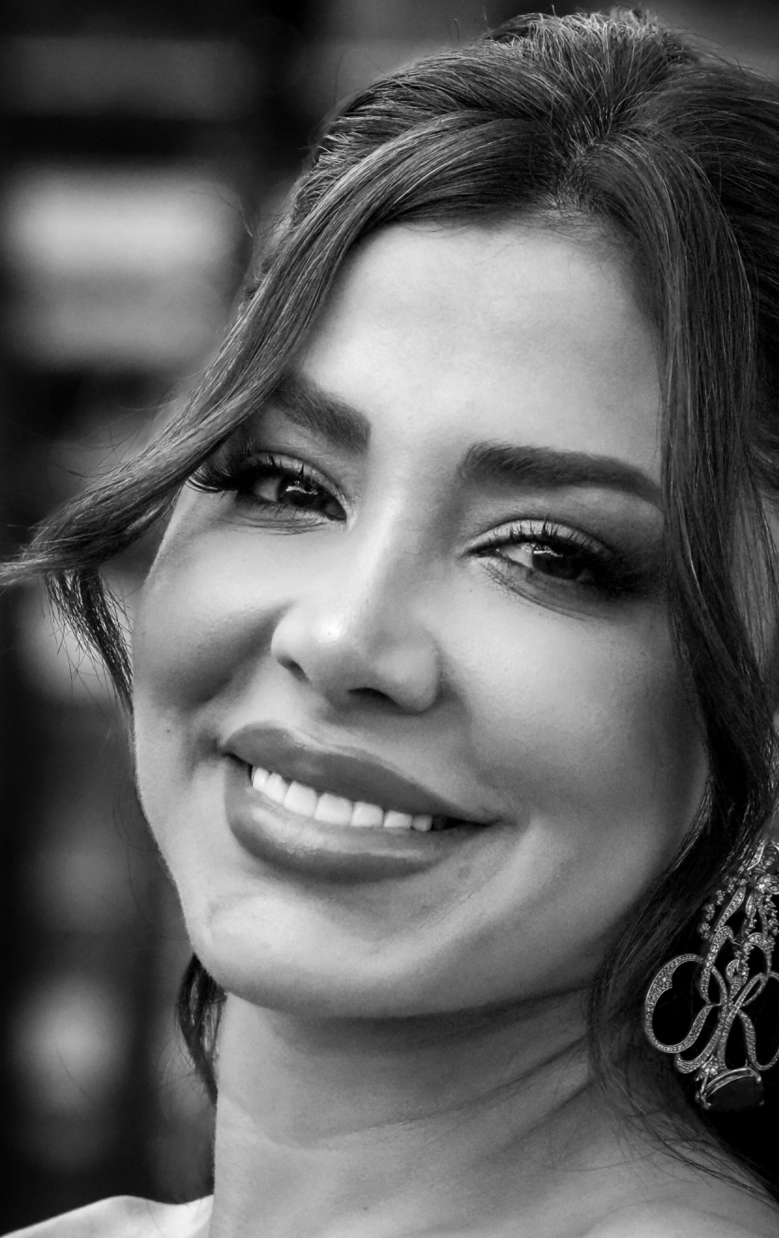 Portrait of a young woman smiling with elegant earrings in black and white.
