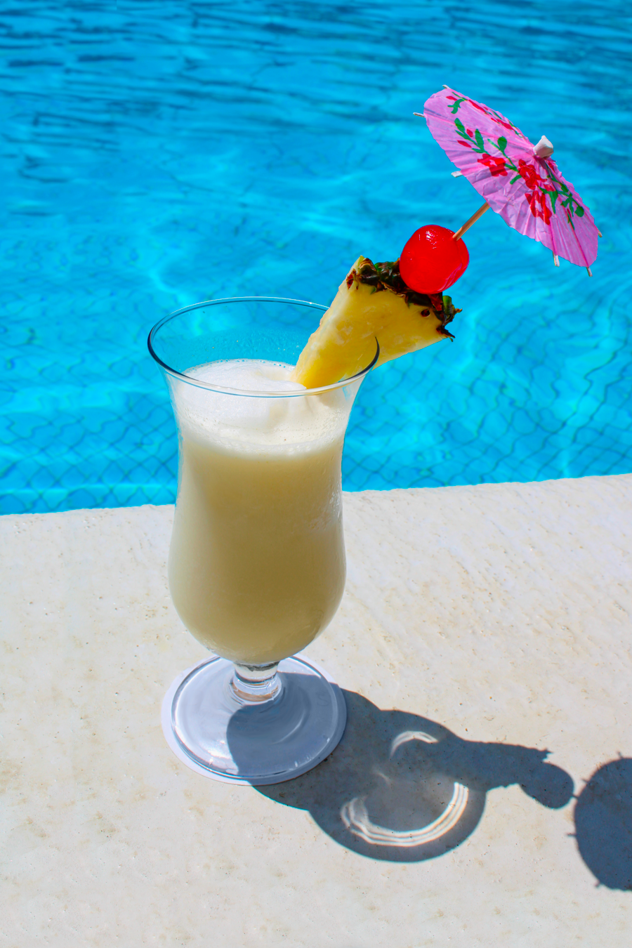 Tropical drink with an umbrella beside a swimming pool