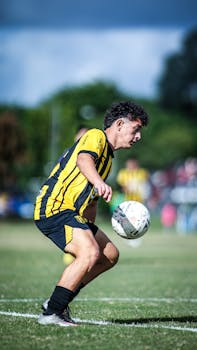 Focused soccer player in yellow sportswear heads the ball during an outdoor match.