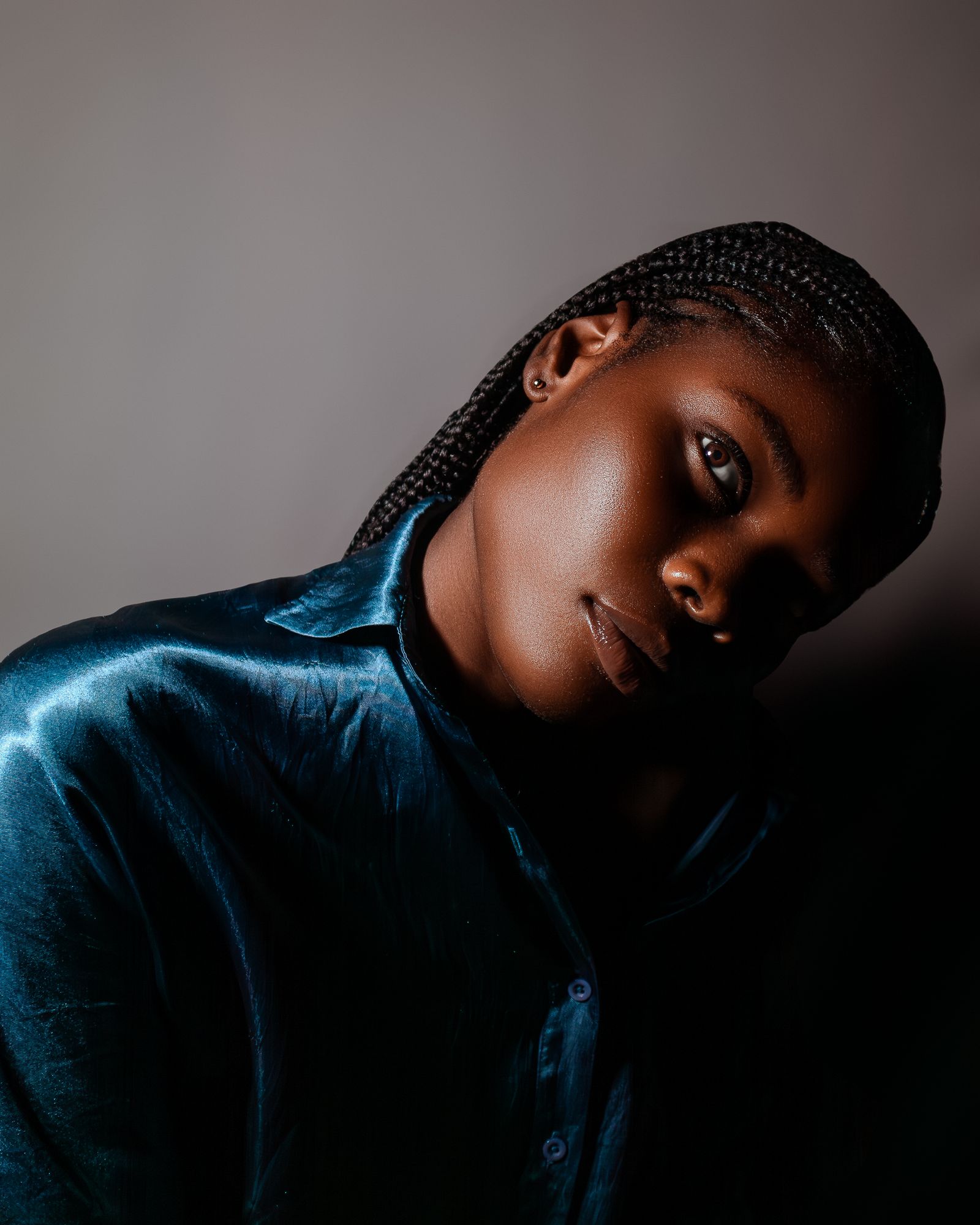 A woman in a satin shirt, the shoulder sitting cleanly in studio light.
