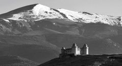 Black and white view of Castillo de La Calahorra set before snowcapped mountains in Spain.