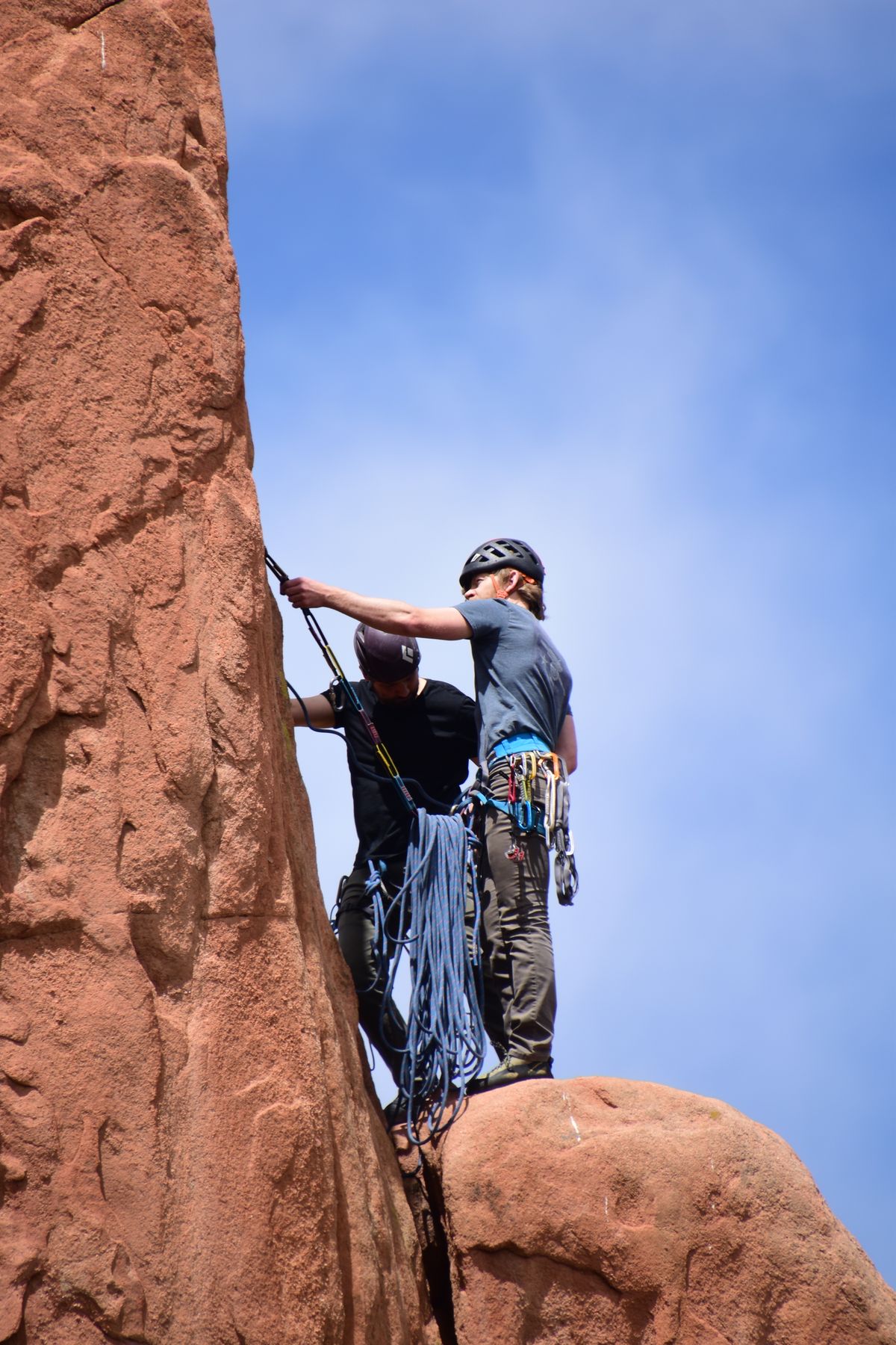 Two climbers with helmets and gear ascending a cliff