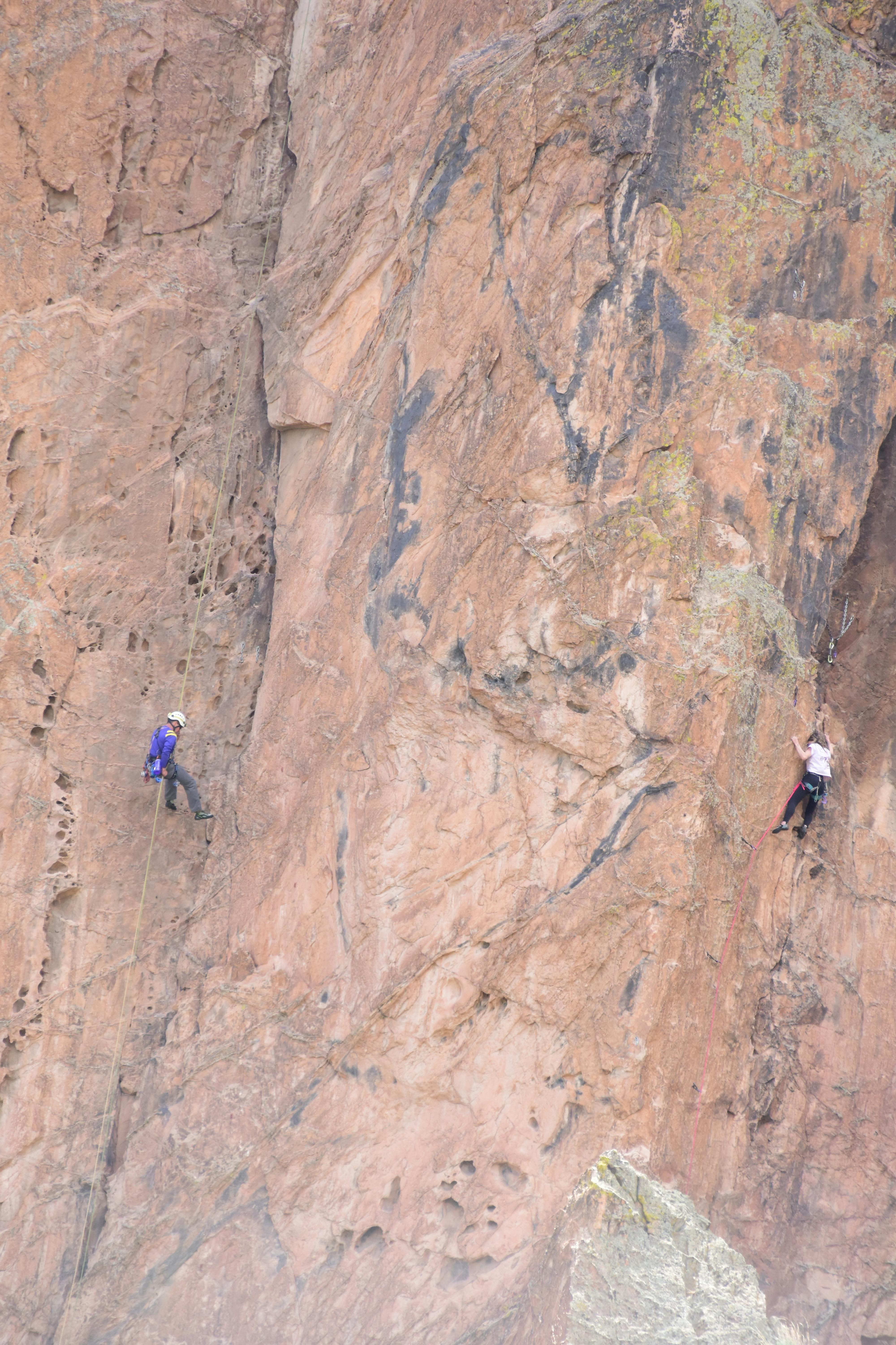 Two rock climbers ascend a steep cliff face, showcasing adventure and skill.
