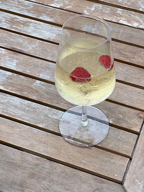 A glass of wine with raspberries on top