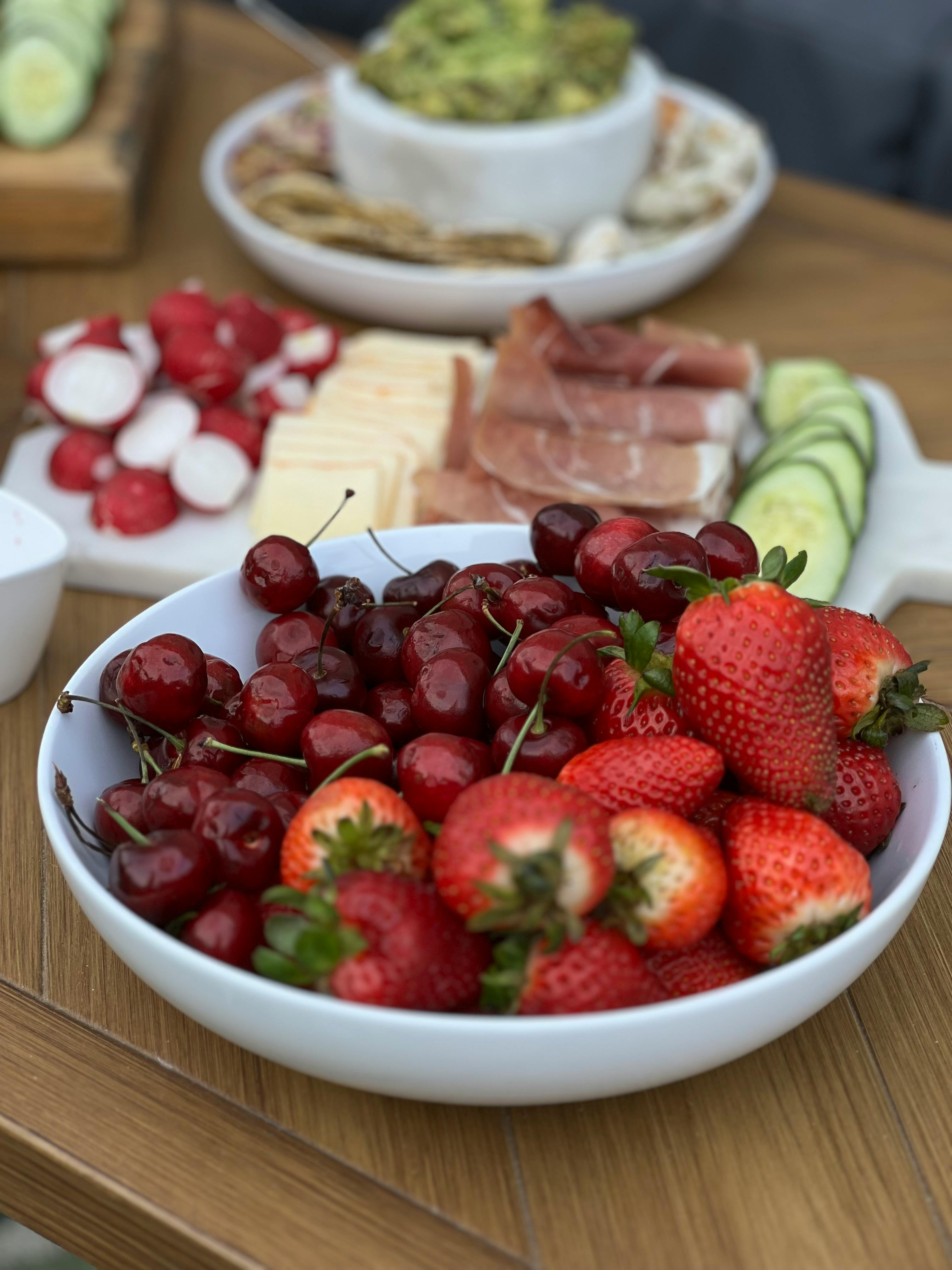 Delicious assortment of fruits, cheese, and snacks on a wooden table, perfect for a picnic.