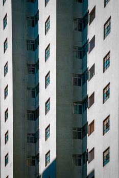 Vertical shot of a modern apartment building with geometric concrete facades and shadows.