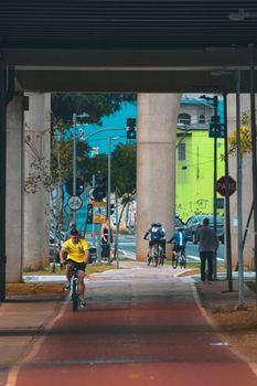 Cyclists and pedestrians on a vibrant urban bike lane under a bridge.