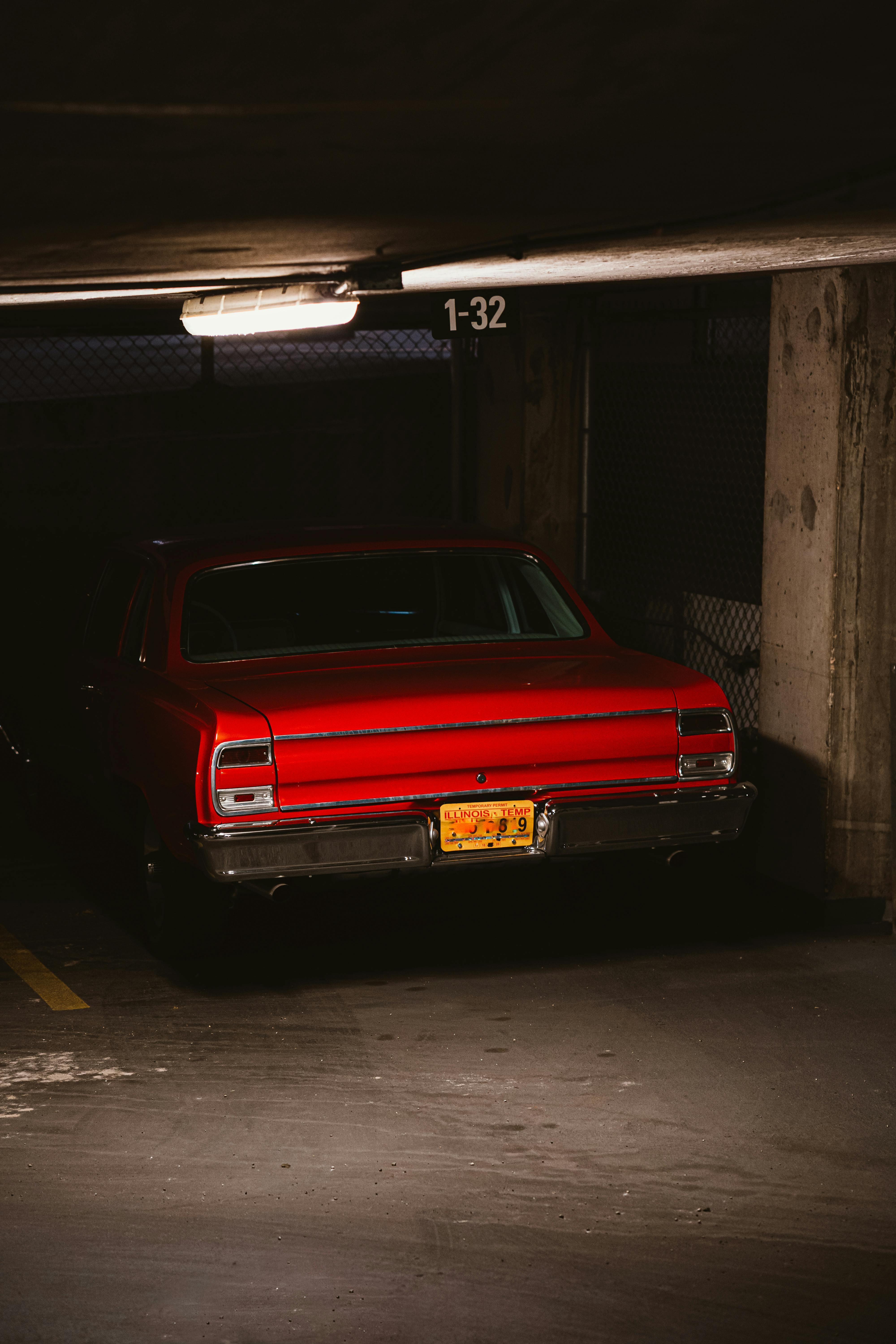 photo of red muscle car parked in underground parking spot