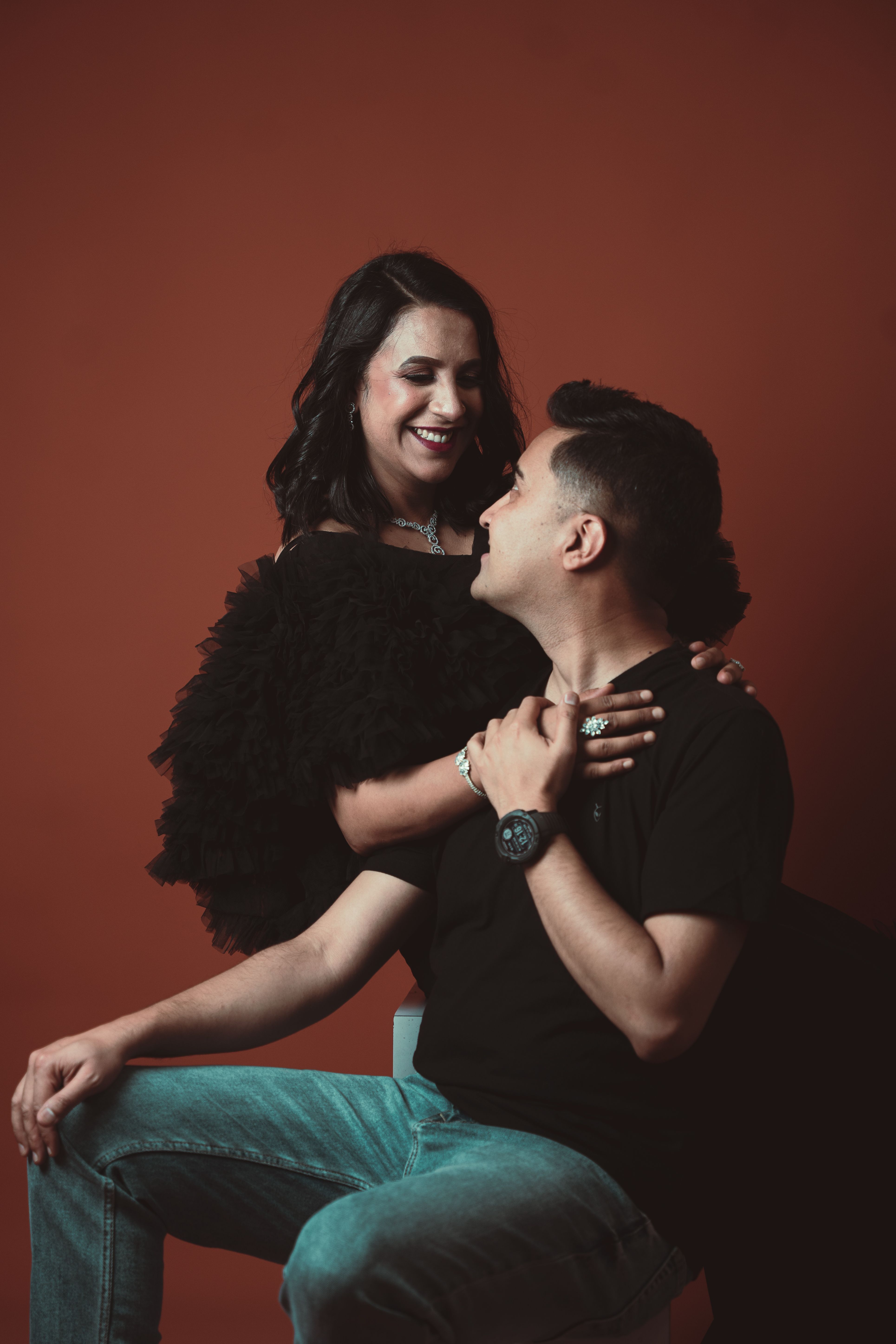 A joyful couple shares a loving moment in a fashionable studio photoshoot.