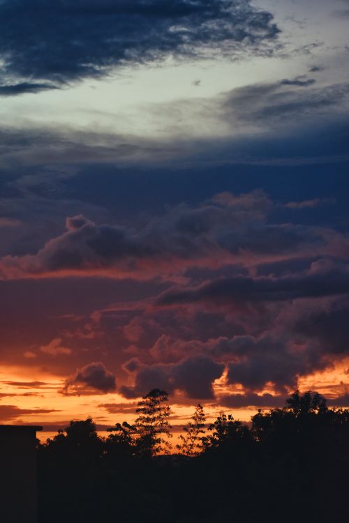 Free A breathtaking sunset with vibrant clouds and rich colors painting the sky. Stock Photo